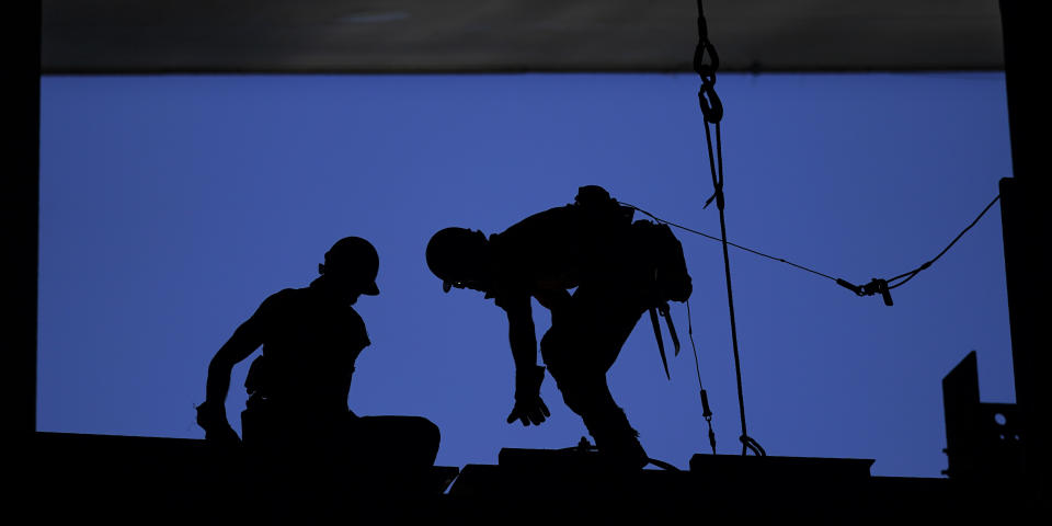 Workers are silhouetted against a blue sky as they work on a beam, Tuesday, Sept. 1, 2020, at the Climate Pledge Arena in Seattle, the home of the Seattle Kraken NHL hockey team. Sometime in the late summer or early fall of 2021, the Kraken will open the new facility -- at a cost that will likely total $1 billion by the time it's done -- and become the NHL's 32nd franchise. (AP Photo/Ted S. Warren)