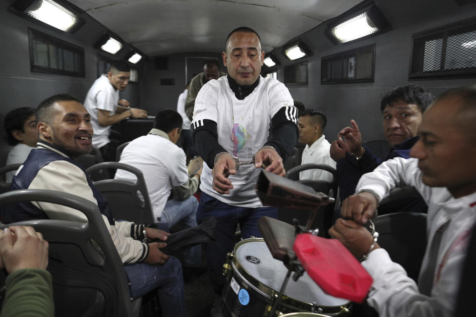 In this July 19, 2019 photo, inmate Martin Reano is passed an instrument inside an armored bus that will transport him and fellow inmates to the Peruvian capital for a classical music session at the national theater, as they leave the prison grounds in Callao, Peru. Sentenced to 20 years in prison for murder, the chance to play an instrument is liberating for Reano. (AP Photo/Martin Mejia)