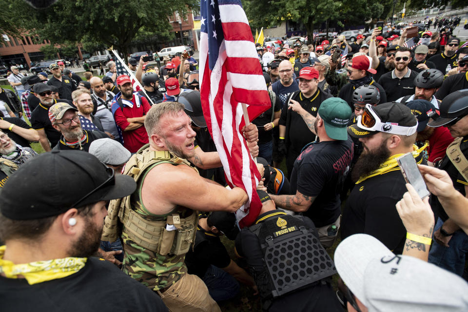 Joseph Oakman and fellow Proud Boys plant a flag in Tom McCall Waterfront Park during an "End Domestic Terrorism" rally in Portland, Ore., on Saturday, Aug. 17, 2019. Portland Mayor Ted Wheeler said the situation was "potentially dangerous and volatile" but as of early afternoon most of the right-wing groups had left the area via a downtown bridge and police used officers on bikes and in riot gear to keep black clad, helmet and mask-wearing anti-fascist protesters — known as antifa — from following them. (AP Photo/Noah Berger)