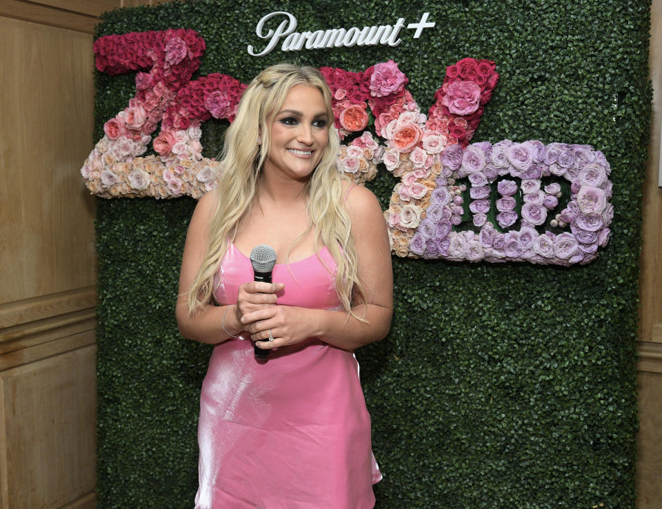 Close-up of Jamie Lynn at a media event and holding a microphone