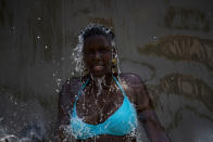 A woman cools off in a water fountain at Madureira Park amid a heat wave in Rio de Janeiro, Brazil, Wednesday, Nov. 15, 2023. (AP Photo/Bruna Prado)