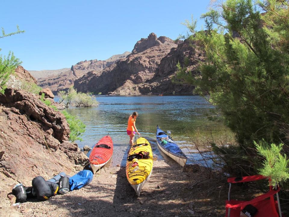 This April 14, 2014 photo shows a kayaker with boats on the shore of the Colorado River in Nevada. Outfitters can pick you up at a hotel in Las Vegas first thing in the morning and have you paddling the river through the Black Canyon some 30 miles from Las Vegas before lunch. The put-in area is near the Hoover Dam, a federal security zone, so watercraft must be transported by an authorized livery service, whether you bring your own gear, rent boats or sign up for a guided trip. (AP Photo/Karen Schwartz)