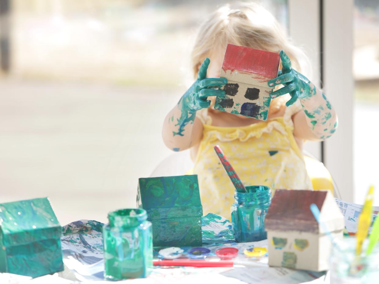 Young girl painting small cardboard houses