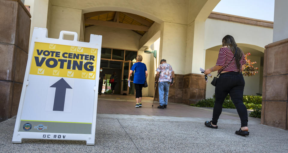 People walk past a sign that with an arrow that reads: Vote Center Voting.