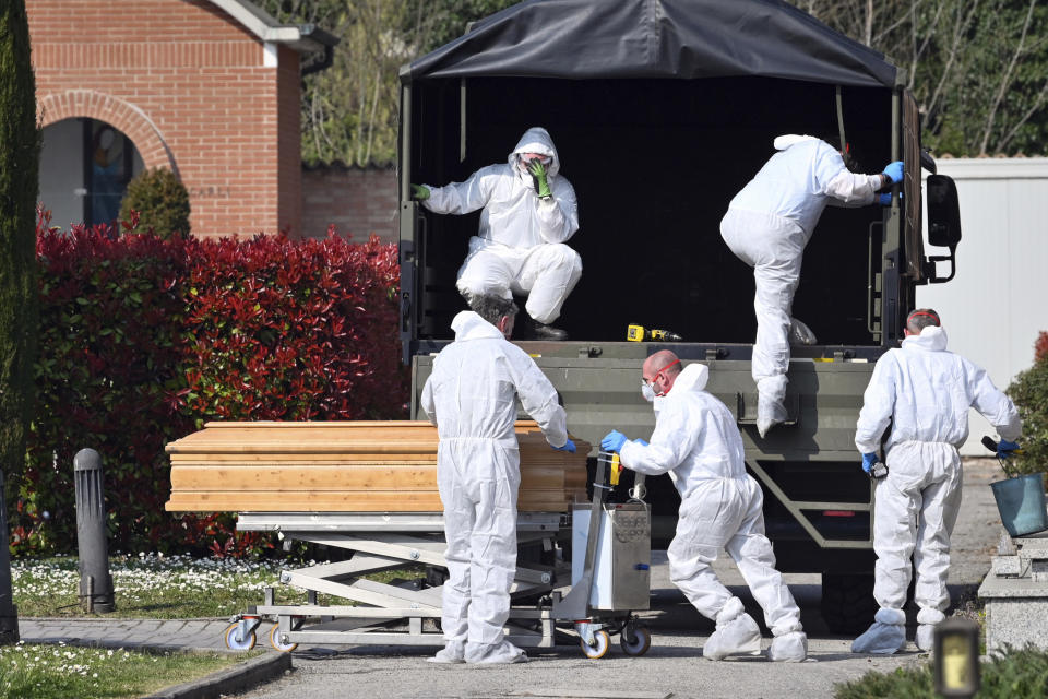 FILE - In this March 21, 2020 file photo, coffins are downloaded at the Ferrara cemetery, northern Italy, from a military convoy coming from Bergamo, a city at the epicenter of the coronavirus outbreak in northern Italy. Italy is seeing a slight stabilizing in its confirmed coronavirus infections two weeks into the world’s most extreme nationwide shutdown, but the virus is taking its silent spread south after having ravaged the health care system in the north. The new coronavirus causes mild or moderate symptoms for most people, but for some, especially older adults and people with existing health problems, it can cause more severe illness or death. (Massimo Paolone/LaPresse via AP, file)