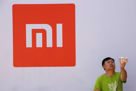 A man takes a selfie in front of the logo of Xiaomi at a venue for the launch ceremony of Xiaomi's new smart phone Mi Max in Beijing, May 10, 2016. REUTERS/Kim Kyung-Hoon/File Photo