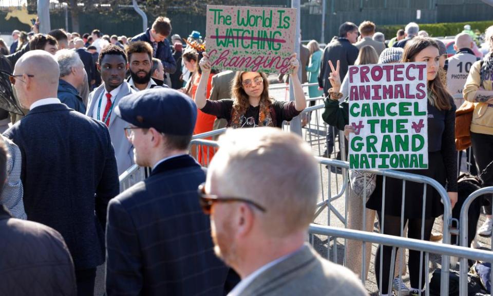 Racing fans walk past protesters before the 2023 Grand National at Aintree