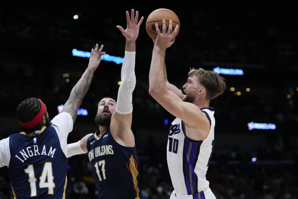 Sacramento Kings forward Domantas Sabonis (10) shoots against New Orleans Pelicans center Jonas Valanciunas (17) and forward Brandon Ingram (14) in the second half of an NBA basketball game in New Orleans, Wednesday, Nov. 22, 2023. The Pelicans won 117-112. (AP Photo/Gerald Herbert)