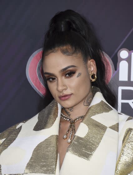 Kehlani poses for pictures wearing a gold and white jacket