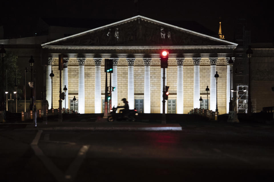 FILE - A man rides a motorbike as he passes by the National Assembly during curfew in Paris, Saturday, Oct. 17, 2020. Elections for the National Assembly are organized in two rounds on June 12 and June 19, 2022. All 577 seats are up for grabs, and each winner will serve a five-year term. (AP Photo/Lewis Joly, File)