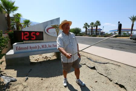 Palm Springs resident Benito Almojuela takes a selfie near a thermometer sign which reads 125 degrees in Palm Springs, California, June 20, 2016. REUTERS/Sam Mircovich