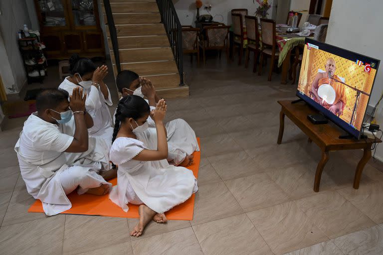 Una familia budista sigue una ceremonia religiosa a través de la televisión con motivo de Vesak