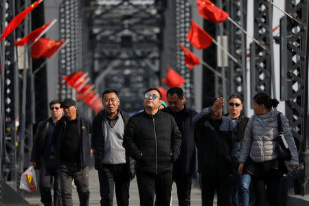 Tourists walk on the Broken Bridge, bombed by the U.S. forces in the Korean War and now a tourist site, over the Yalu River that divides North Korea and China, in Dandong, China's Liaoning province, April 1, 2017. REUTERS/Damir Sagolj