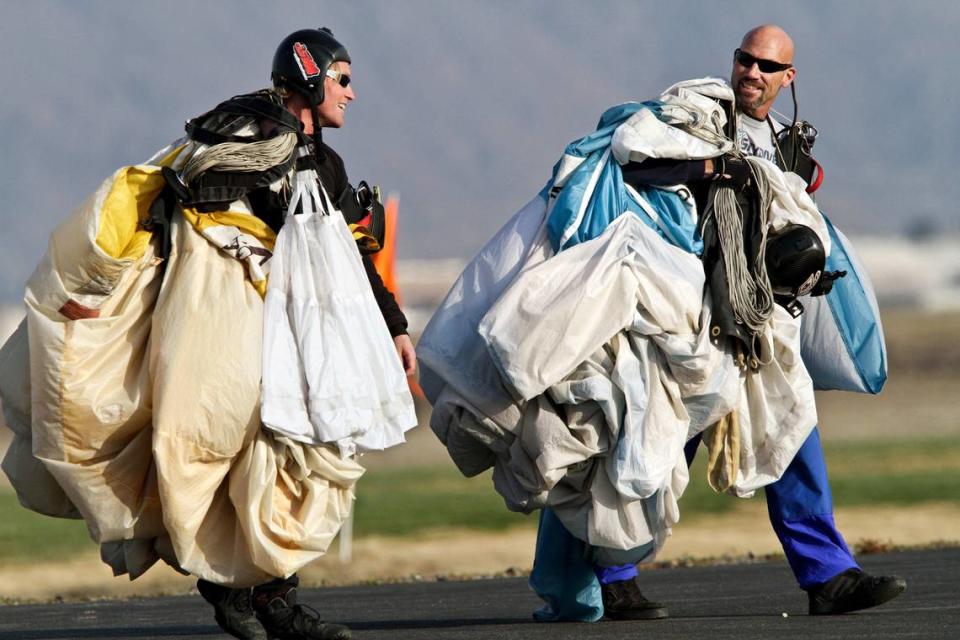 Instructors Rob Wallace, left, and Jeremie Chapin walk with folded up tandem parachutes after taking students skydiving at Skydive Perris in Riverside County on Feb. 20, 2012.