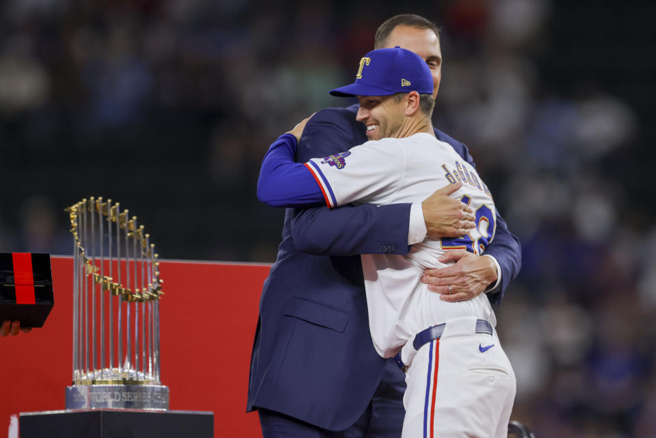 Texas Rangers pitcher Jacob deGrom, front, hugs general manager Chris Young, back, during the World Series ring ceremony before a baseball game against the Chicago Cubs, Saturday, March 30, 2024, in Arlington, Texas. (AP Photo/Gareth Patterson)