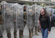 FILE - In this February 11, 2020 file photo,a protester shouts slogans in front of army soldiers during a protest against a parliament session vote of confidence for the new government in downtown Beirut, Lebanon. The currency collapse has wiped out the salaries of the U.S.-backed Lebanese military, placed unprecedented pressure on the army's operational capabilities with some of the highest attrition rates over the past two years, and raised concerns about its ability to continue playing a stabilizing role while sectarian tensions and crime are on the rise.(AP Photo/Hussein Malla, File)