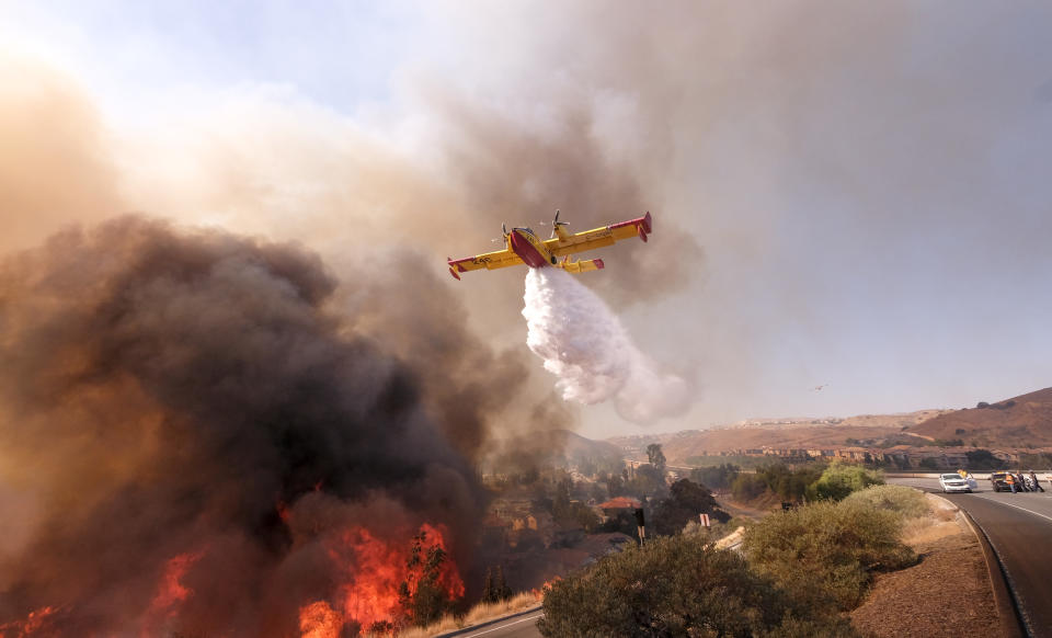 An air tanker drops water on a fire along the Ronald Reagan Freeway in Simi Valley, California on Monday. Image: AP