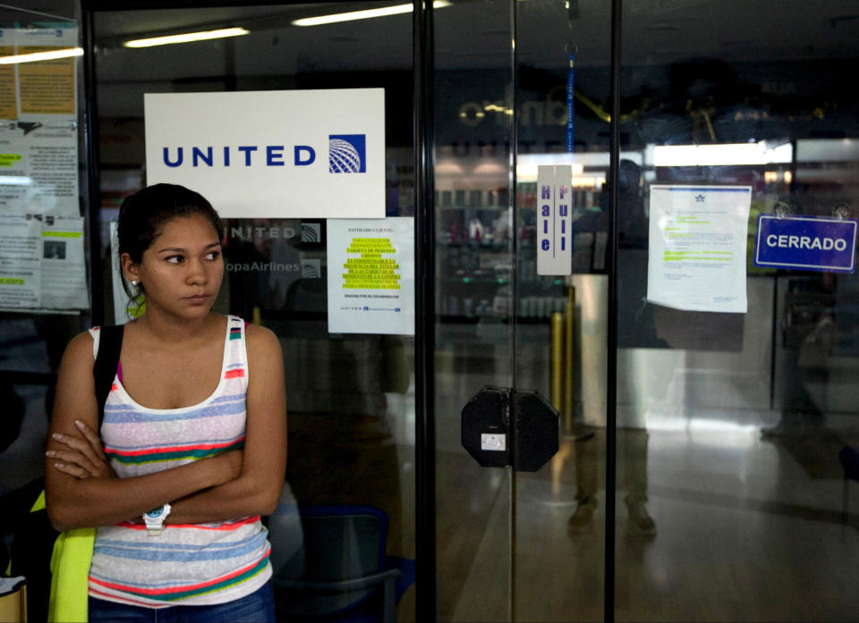 A woman stands outside a closed United Airlines office in Caracas, Venezuela, Friday, Jan. 24, 2014. Delta, American Airlines and Panama's Copa Airlines were also among carriers whose offices were either closed or had halted sales on Friday after the government devalued the local currency for flights abroad. (AP Photo/Alejandro Cegarra)