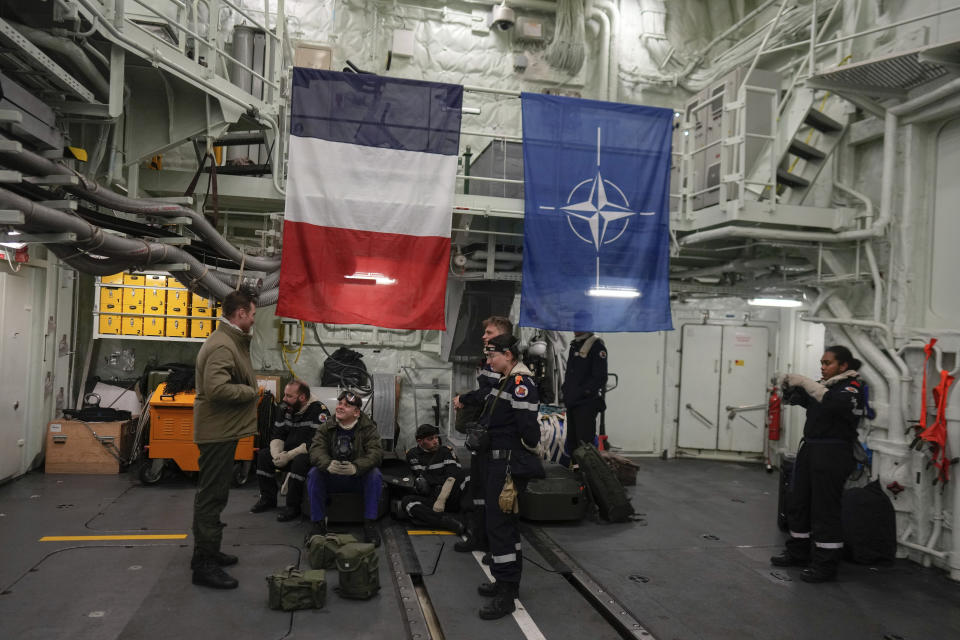 French sailors stand in front of the flags of France and NATO as the French navy frigate Normandie patrols in a Norwegian fjord, north of the Arctic circle, for a reconnaissance patrol, Wednesday March 6, 2024. The French frigate is part of a NATO force conducting exercices in the seas, north of Norway, codenamed Steadfast Defender, which are the largest conducted by the 31 nation military alliance since the cold war. (AP Photo/Thibault Camus)