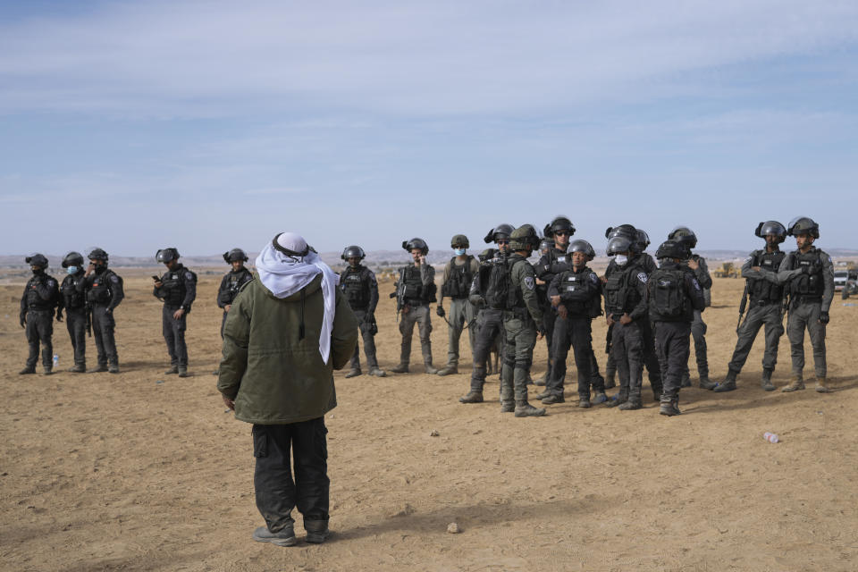 Israeli security forces stand guard as Bedouins protest against tree-planting by the Jewish National Fund on disputed land near the beduin village of al-Atrash in the Negev desert, southern Israel, Wednesday, Jan. 12, 2022. The conflict in southern Israel, which is home to Bedouin villages unrecognized by the state, has divided the Israeli government with Foreign Minister Yair Lapid called for halting the tree-planting while the Islamist Ra'am party has threatened to withhold its votes in parliament in protest. (AP Photo/Mahmoud Illean)
