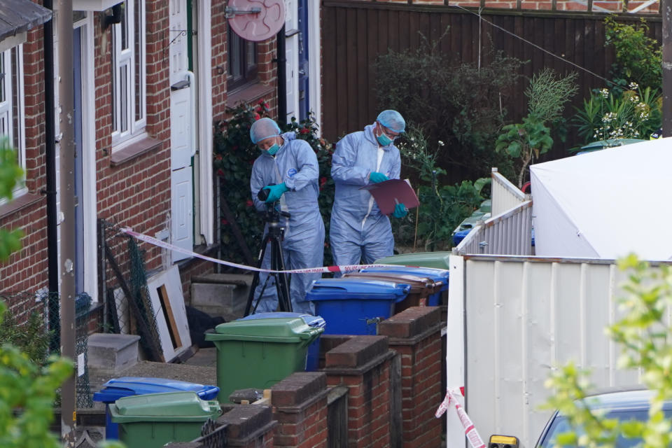 Police officers in forensic suits examined the house where the stabbings took place (SWNS)