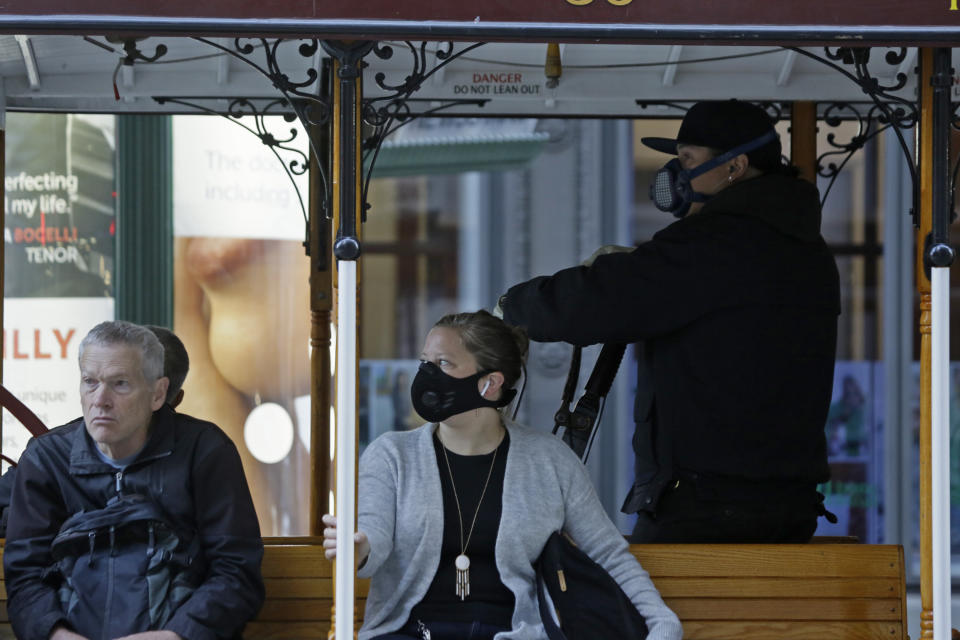 A California Street cable car operator and passenger wear breathing masks to protect against smoke from wildfires Monday, Oct. 28, 2019, in San Francisco. A wildfire that has been burning in Northern California's wine country since last week grew overnight as nearly 200,000 people remain under evacuation orders. (AP Photo/Eric Risberg)