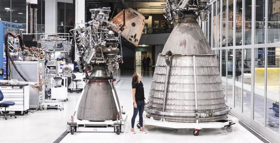 A person standing in between a Raptor and Raptor Vacuum engine.