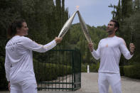 The first torch bearer, Greek olympic gold medalist Stefanos Douskos, right, passes the flame to first French torchbearer, three-time Olympic medallist Laure Manaudou, after the official ceremony of the flame lighting for the Paris Olympics, at the Ancient Olympia site, Greece, Tuesday, April 16, 2024. The flame will be carried through Greece for 11 days before being handed over to Paris organizers on April 26. (AP Photo/Thanassis Stavrakis)