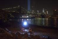 A couple sitting along the banks of the East River are light by a flash as they pose for a self portrait while having dinner near the Brooklyn Bridge as the Tribute in Light illuminates the sky over the Lower Manhattan skyline a day ahead of the 12-year anniversary of the 9/11 attacks in the Brooklyn borough of New York on September 10, 2013. (REUTERS/Adrees Latif)