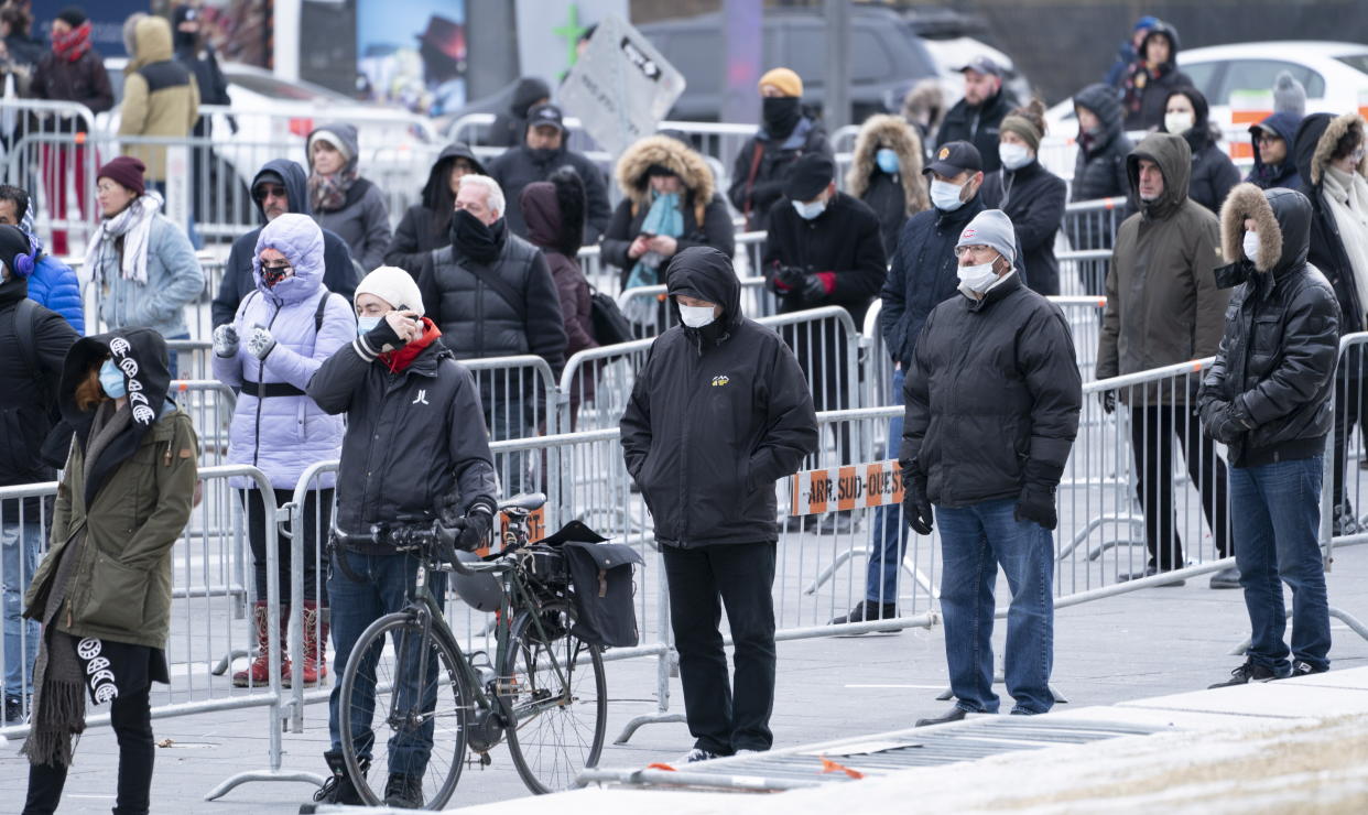 People wait in line to get into a walk-in test clinic for COVID-19, the disease caused by the new coronavirus, in Montreal on Monday, March 23, 2020. (Paul Chiasson/The Canadian Press via AP)