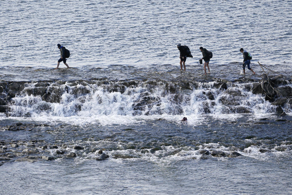 Migrants cross the Maritsa river on their way to the Greek border, near Edirne, Turkey, Tuesday, March. 3, 2020. Migrants and refugees hoping to enter Greece from Turkey appeared to be fanning out across a broader swathe of the roughly 200-kilometer-long land border Tuesday, maintaining pressure on the frontier after Ankara declared its borders with the European Union open. (AP Photo/Darko Bandic)