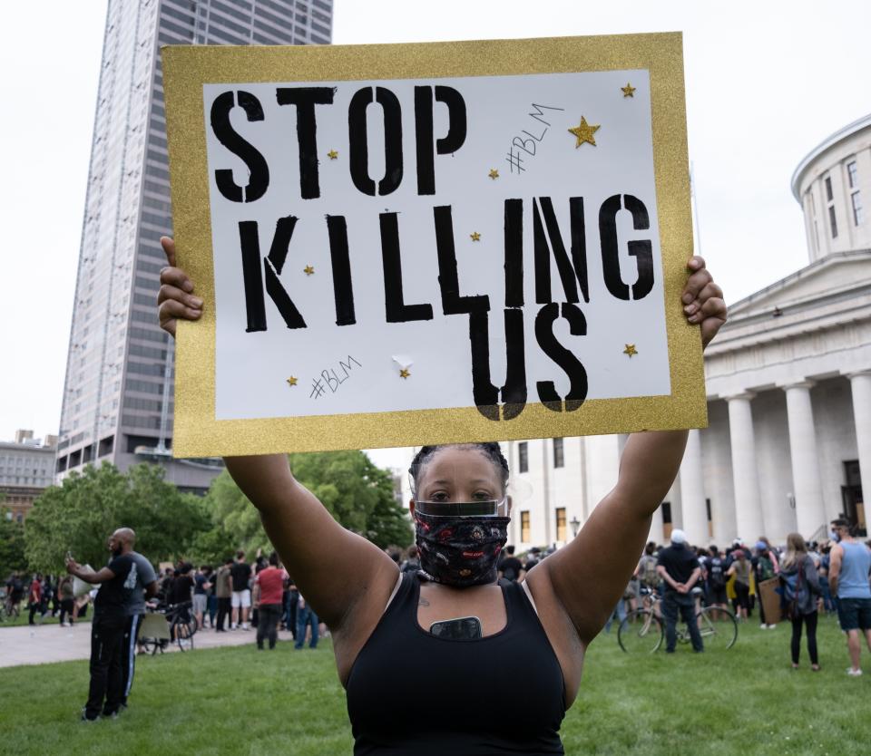 A demonstrator holds a sign reading "Stop Killing Us" in front of the Ohio Statehouse in Downtown Columbus, Ohio June 1, 2020 to peacefully protest the death of George Floyd. - Local US leaders appealed to citizens to give constructive outlet to their rage over the death of an unarmed black man in Minneapolis, while night-time curfews were imposed in cities including Washington, Los Angeles and Houston. (Photo by SETH HERALD / AFP) (Photo by SETH HERALD/AFP via Getty Images)