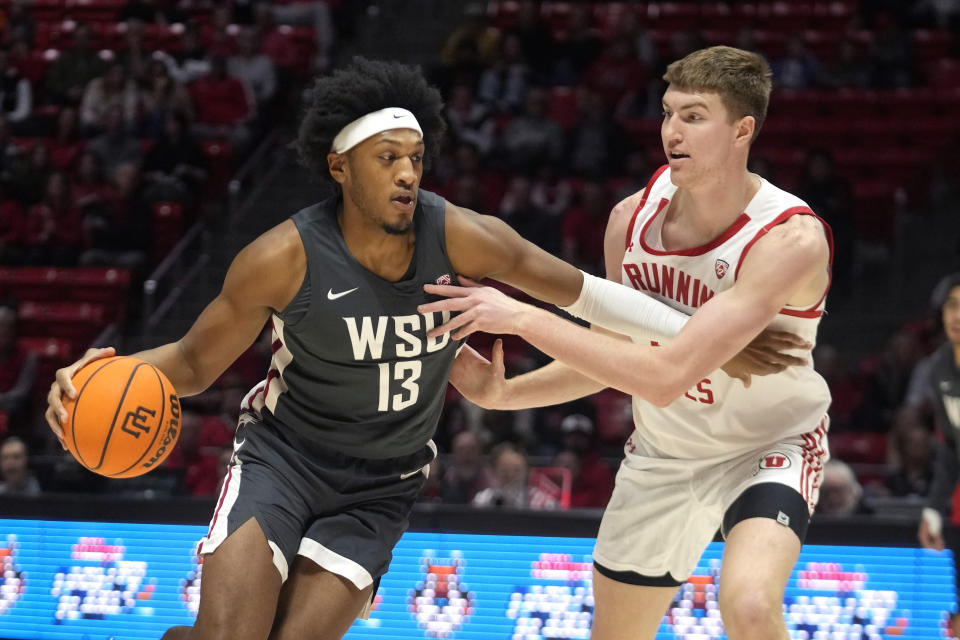 Washington State forward Isaac Jones (13) drives as Utah center Lawson Lovering, right, defends during the first half of an NCAA college basketball Friday, Dec. 29, 2023, in Salt Lake City. (AP Photo/Rick Bowmer)