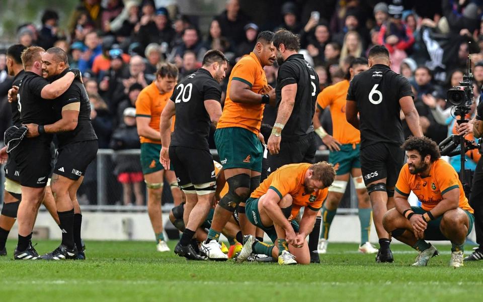 Australia players sink to their knees as New Zealand celebrate at the final whistle