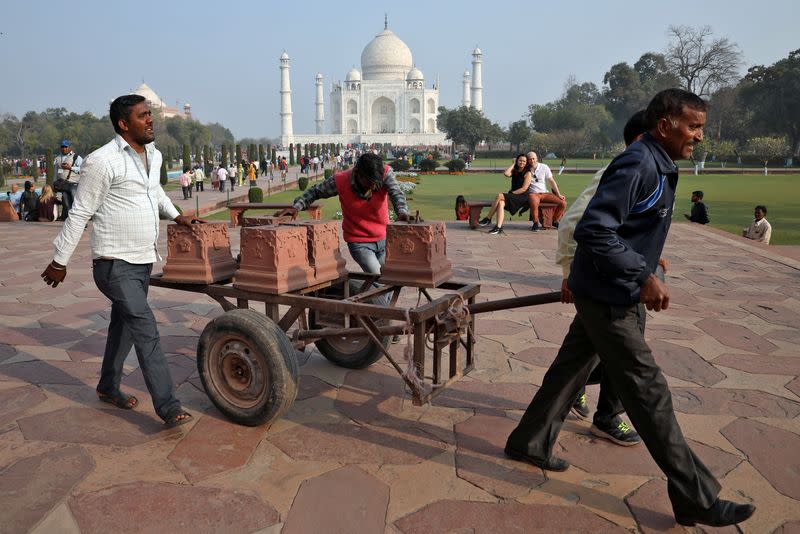 Workers move carved stones on a handcart inside the historic Taj Mahal premises in Agra