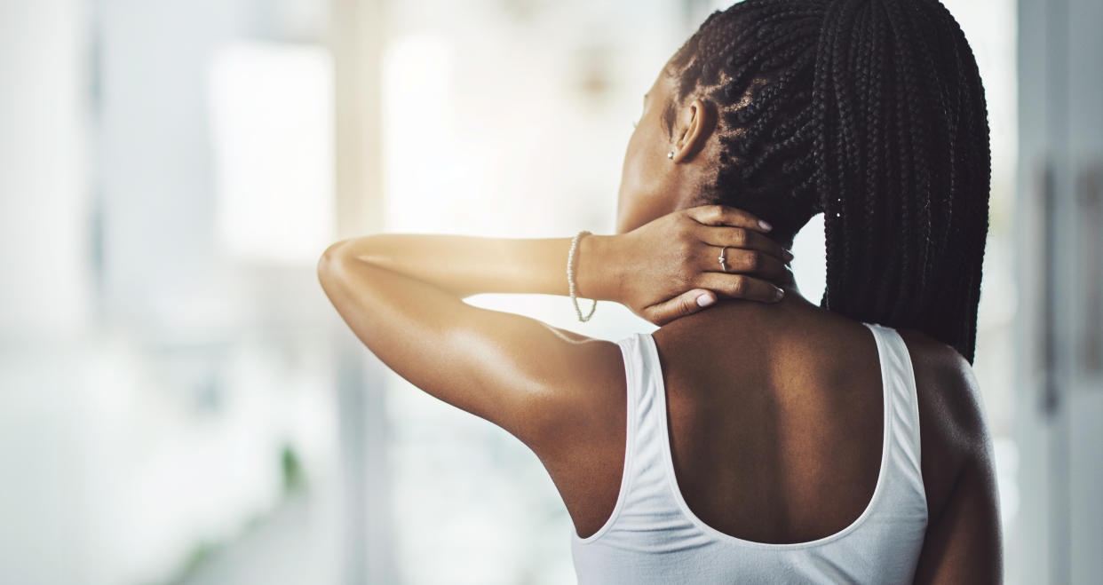 Bad posture. Rearview shot of a young woman experiencing neck pain while working out