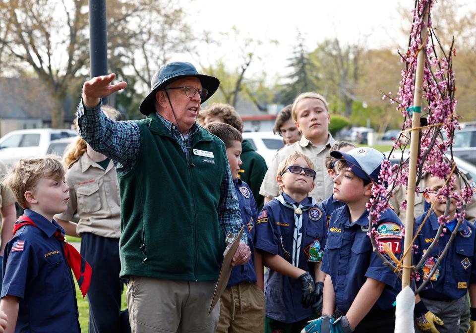 Paul Pfeifer, managing director of Tipton's Hidden Lake Gardens, explains the importance of Earth Day to a crowd of people, including youth scout members Monday, April 22, 2024, during an Earth Day tree planting ceremony at the Tecumseh District Library.