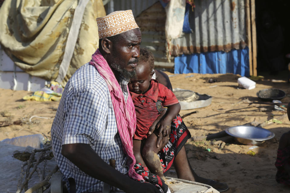 Hassan Mohamed Yusuf, 45 year old father, sits with his family at their make shift shelter Dayniile camp, in Mogadishu, Somalia on Thursday Dec. 17, 2020. As richer countries race to distribute COVID-19 vaccines, Somalia remains the rare place where much of the population hasn't taken the coronavirus seriously. Some fear that’s proven to be deadlier than anyone knows. (AP Photo/Farah Abdi Warsameh)