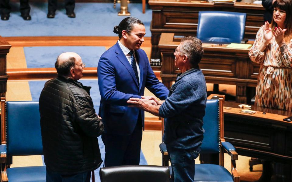 Wab Kinew, the Manitoba Premier, centre, apologises to Richard Beauvais, right, and Eddy Ambrose, left