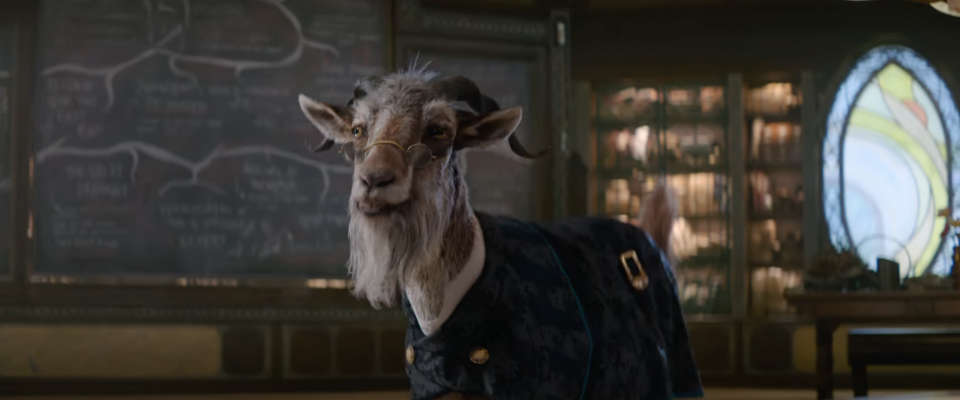 Goat wearing a jacket in a room with chalkboard diagrams behind it