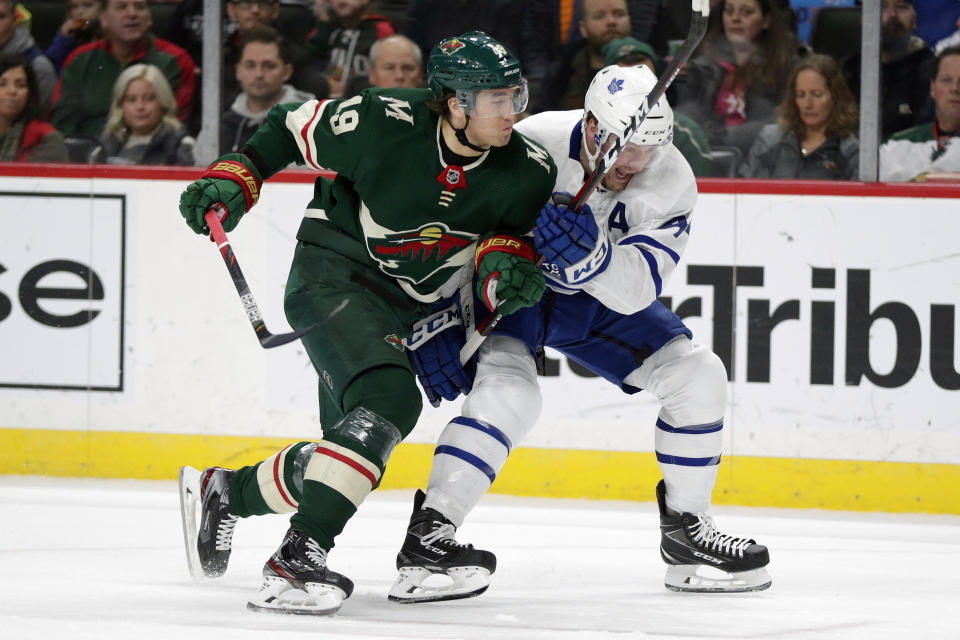 Minnesota Wild Luke Kunin (19) and Toronto Maple Leafs Morgan Rielly (44) vie for a puck in the first period of an NHL hockey game Tuesday, Dec. 31, 2019, in St. Paul, Minn. (AP Photo/Andy Clayton-King)