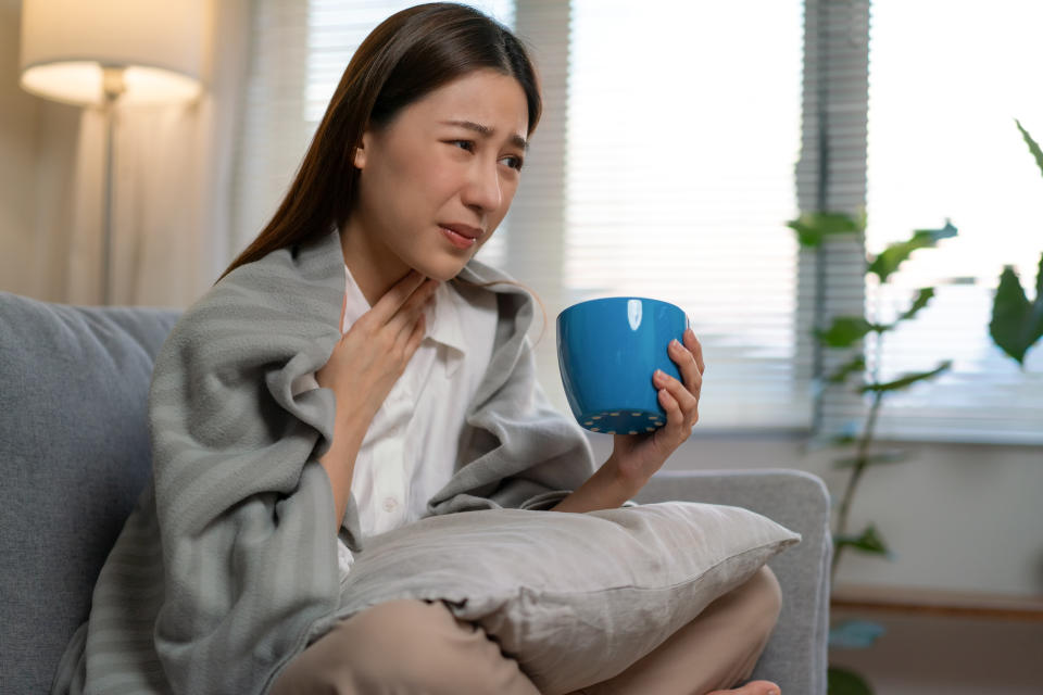 Asian woman lying on her bed at home while suffering from the flu.