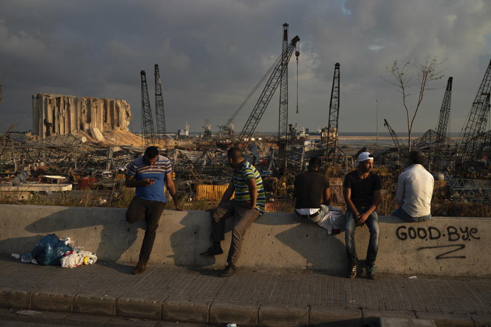 People sit near the site of last week's explosion that hit the seaport of Beirut, Lebanon, Tuesday, Aug. 11, 2020. (AP Photo/Felipe Dana)