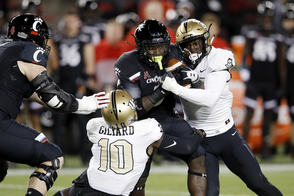 Michael Warren II #3 of the Cincinnati Bearcats gets tackled by Nate Evans #44 and Eriq Gilyard #10 of the Central Florida Knights in the first quarter. (Getty)