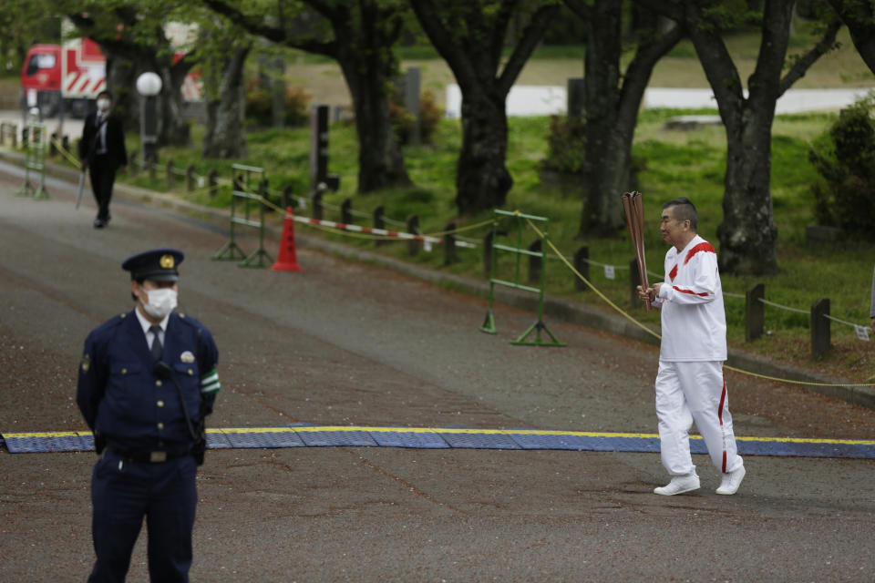 Entertainer Katsura Bunshi IV, participating as an Olympic torch relay runner, warms up as he waits for his preceding runner during the first day of the Osaka round at a former Expo site in Suita, north of Osaka, western Japan, Tuesday, April 13, 2021. The Tokyo 2020 Olympic kick-off event which was rescheduled due to the coronavirus outbreak was yet rearranged to hold at the former Expo park, instead of public streets, to close off the audience from the even, following the mayor's decision as Osaka has had sharp increases in daily cases since early March. (AP Photo/Hiro Komae)