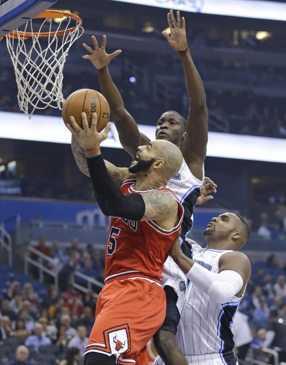 Chicago Bulls' Carlos Boozer (5) gets off a shot as he gets past Orlando Magic's Victor Oladipo, center, and Glen Davis during the first half of an NBA basketball game in Orlando, Fla., Wednesday, Jan. 15, 2014. (AP Photo/John Raoux)