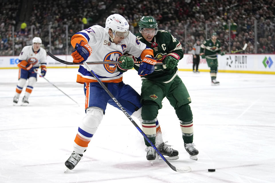 New York Islanders left wing Anders Lee, left, and Minnesota Wild defenseman Jared Spurgeon battle for the puck during the second period of an NHL hockey game Tuesday, Feb. 28, 2023, in St. Paul, Minn. (AP Photo/Abbie Parr)