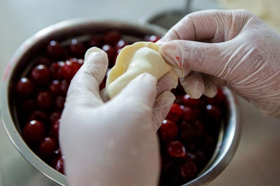 A volunteer of the Movement for the Support of the Zakarpattia Military makes varenyky with cherries during the Let's Celebrate Kupala to Make Russia Burn! action to raise money for making camouflage nets and ghillie suits in Uzhhorod, Zakarpattia Oblast on July 5, 2022. (Serhii Hudak/ Ukrinform/Future Publishing via Getty Images)