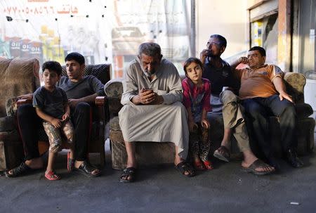 An Iraqi Shi'ite man (C) uses his phone as he sits at an outdoor cafe in Sadr City in Baghdad in this April 29, 2014 file photo. REUTERS/Ahmed Jadallah/Files