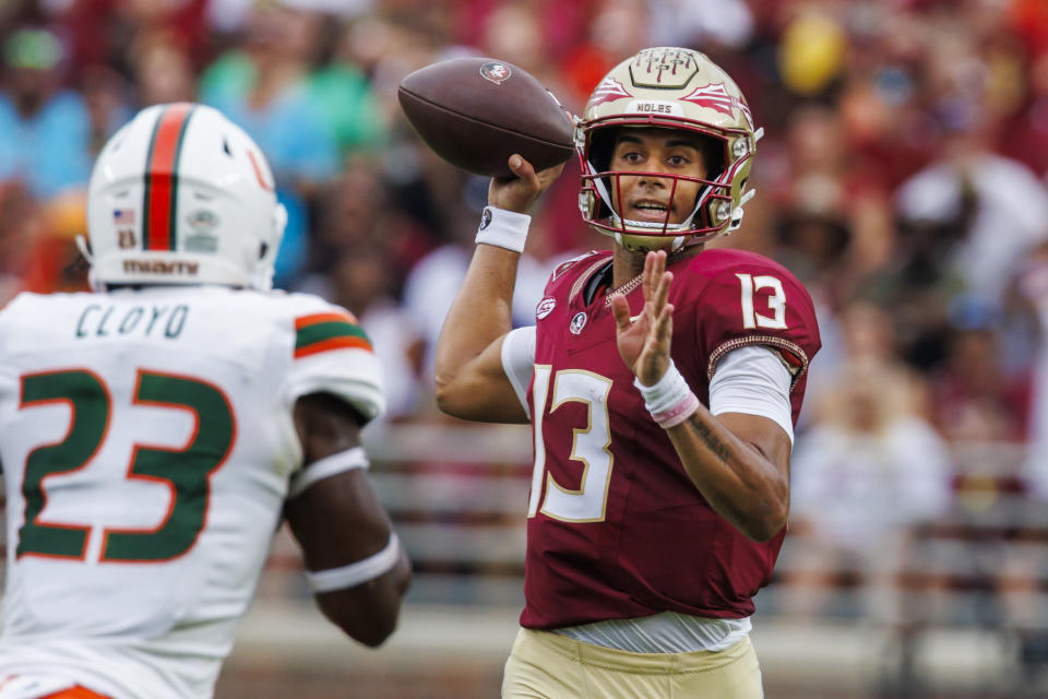 FILE - Florida State quarterback Jordan Travis (13) looks for a receiver as Miami linebacker K.J. Cloyd (23) closes during the first half of an NCAA college football game Nov. 11, 2023, in Tallahassee, Fla. Could the fourth-ranked Seminoles, with a victory against defending national champion and No. 6 Georgia in the Orange Bowl be voted No. 1 in the final Associated Press college football poll? While voters say they would be open-minded to it, the current state of college football’s postseason all but renders the conversation moot. (AP Photo/Colin Hackley, File)